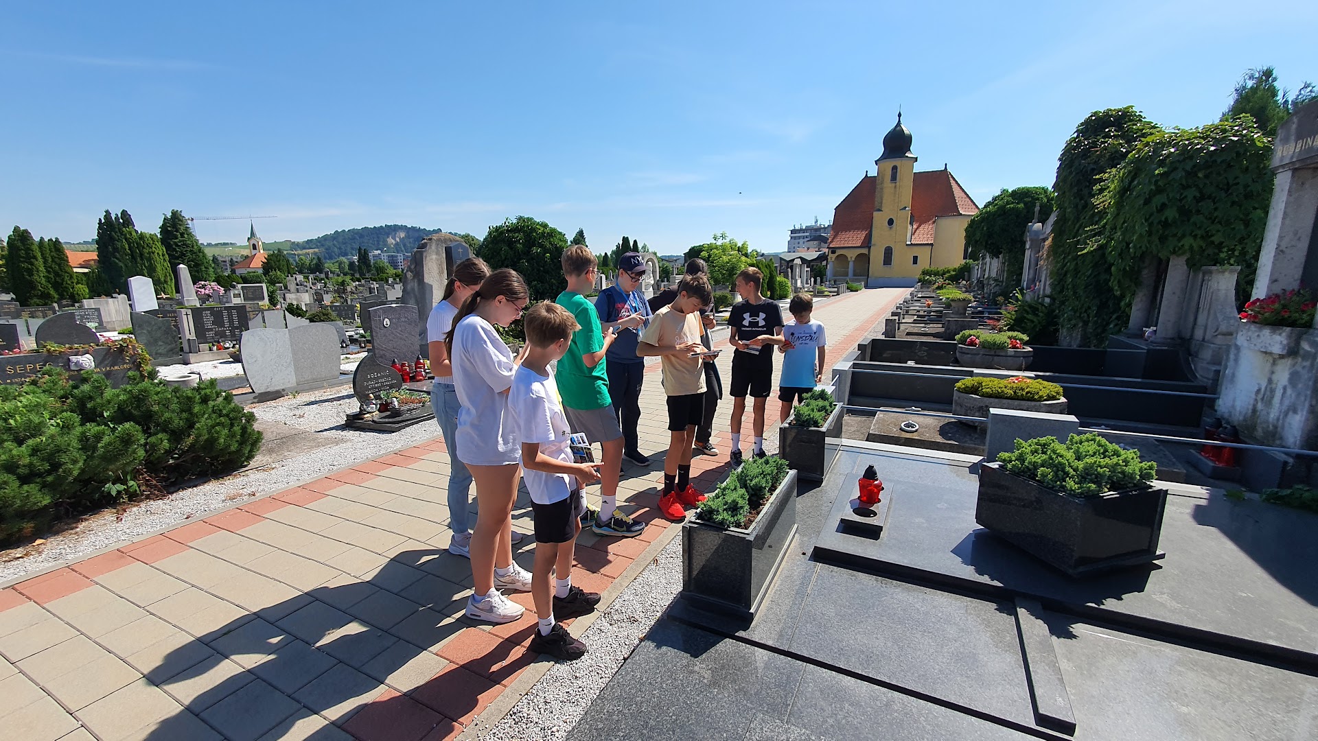 School kids exploring Pobrežje cemetery in Maribor with mobile devices